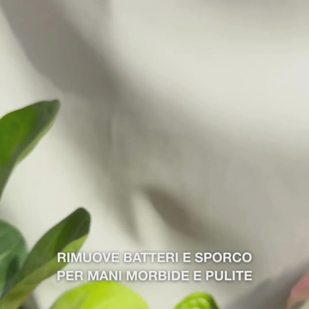 Primo piano di mani che prelevano con il dosatore una schiuma liquida trasparente di colore azzurro chiaro arricchita con Tea Tree Oil nel palmo, quindi la massaggiano delicatamente su palmi, dorso delle mani e tra le dita — la schiuma morbida elimina batteri e sporco, lasciando la pelle morbida e idratata.