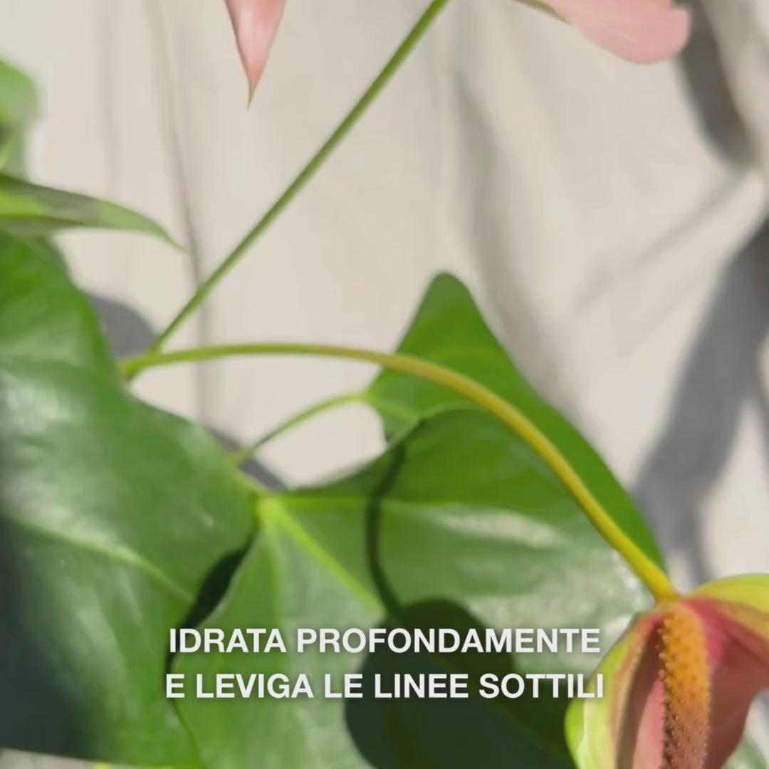 Primo piano di una mano che preleva alcune gocce di un siero viso setoso e trasparente con un contagocce in vetro, appoggiandole sulle punte delle dita e massaggiandolo delicatamente su pelle leggermente umida: la texture leggera e a rapido assorbimento idrata all’istante, riempie le linee sottili e lenisce con acido ialuronico al 2 %, vitamina B5 e olio di tea tree 