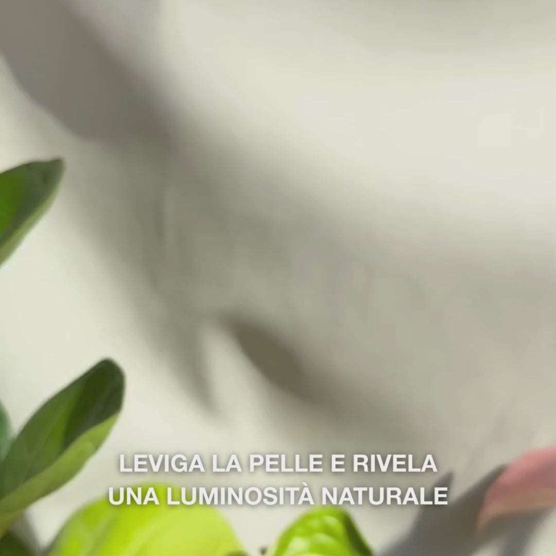Primo piano di una mano che rilascia poche gocce sottili di un siero peeling trasparente e leggero sulle punte delle dita, massaggiandolo delicatamente sulla pelle pulita del viso — la sua consistenza fluida e setosa dissolve visibilmente le cellule morte, affina la texture della pelle e intensifica l’incarnato grazie agli AHA naturali (Lime Pearl), niacinamide e tea tree oil 